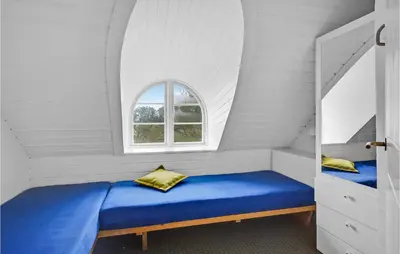 a bedroom with a blue bed and a window at Pee Klims Hus in Brovst