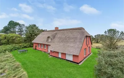 a red house with a roof on a green field at Pee Klims Hus in Brovst
