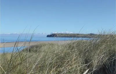 a beach with tall grass in front of the ocean at Holiday Home Svenstibakkevej Denmark Ii in Frøstrup