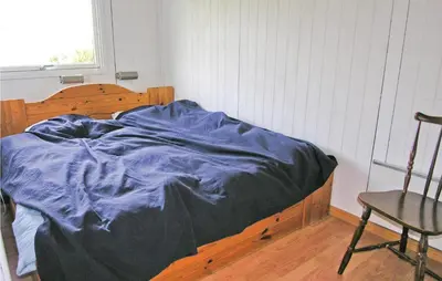 a bed with a blue blanket and a chair in a room at Holiday Home Svenstibakkevej Frøstrup Xii in Frøstrup