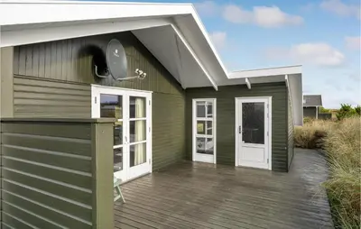 a green house with a white roof and a deck at Holiday Home Svenstibakkevej Denmark in Frøstrup