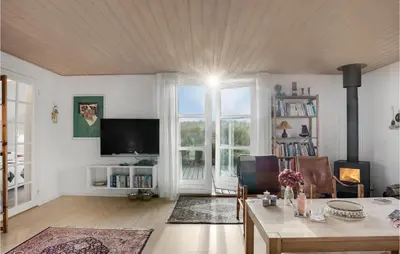 a living room with a table and a tv at Holiday Home Svenstibakkevej Denmark in Frøstrup