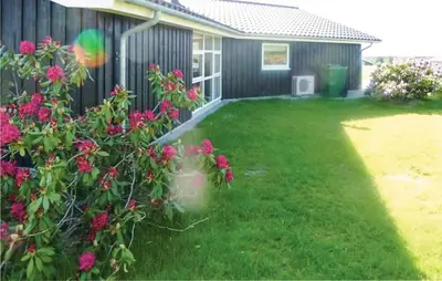 a yard with pink flowers next to a house at Holiday Home Aspevej Fjerritslev Xi in Fjerritslev