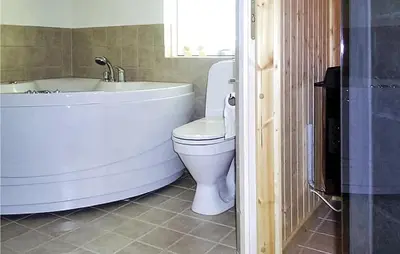 a bathroom with a tub and a toilet and a sink at Holiday Home Aspevej Fjerritslev Xi in Fjerritslev