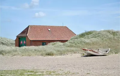 a boat sitting on the beach next to a building at Jydehuset in Fjerritslev