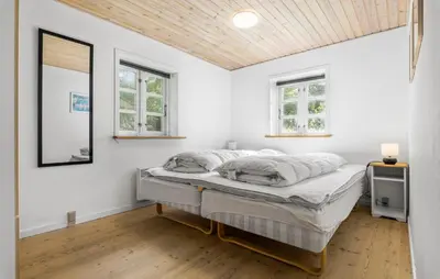 a bedroom with a bed and two windows at Holiday Home Strandvejen Brovst Denm in Brovst