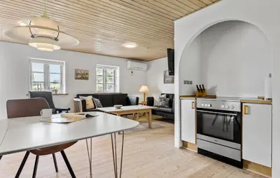 a kitchen and living room with a table and a stove at Holiday Home Strandvejen Brovst Denm in Brovst
