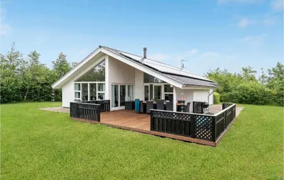 a small white house with a deck in the grass at Holiday Home Kronvildtvej Brovst I in Brovst