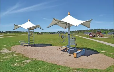 a playground with two white umbrellas in a field at Holiday Home Kronvildtvej Brovst I in Brovst
