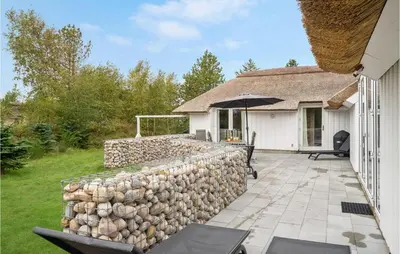 a patio with a retaining wall and an umbrella at Gorgeous Home In Fjerritslev With Wifi in Fjerritslev