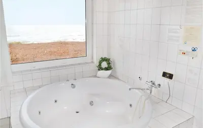 a white bath tub in a bathroom with a window at Holiday Home Sandnæshagevej Frøstrup Iv in Frøstrup