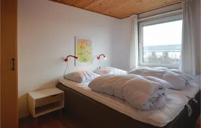 a bedroom with two beds with pillows and a window at Holiday Home Sandnæshagevej Frøstrup Iv in Frøstrup