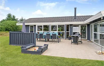 a patio with chairs and a grill in front of a house at 4 Bedroom Stunning Home In Fjerritslev in Fjerritslev