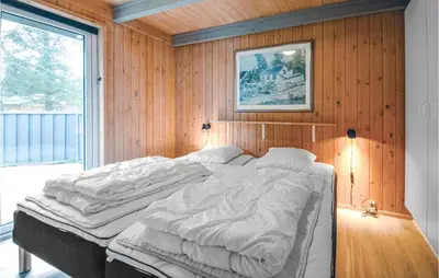 a bedroom with a large bed in a wooden wall at 4 Bedroom Stunning Home In Fjerritslev in Fjerritslev
