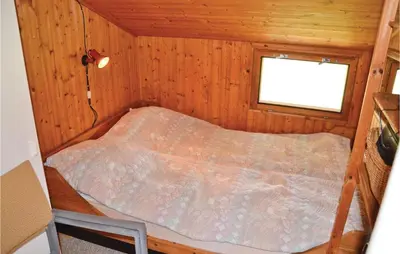 a small bed in a wooden room with a window at Holiday Home Svenstibakkevej Frøstrup in Frøstrup