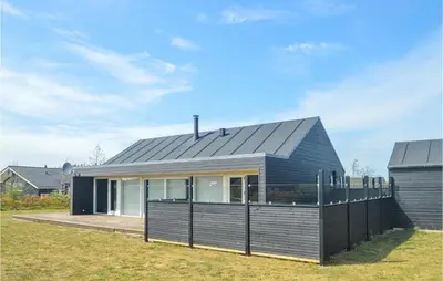 a house with a black roof and a fence at Holiday Home Kronvildtvej Brovst in Brovst