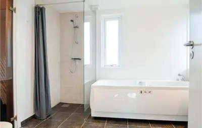 a bathroom with a tub and a sink and a shower at Holiday Home Kronvildtvej Brovst in Brovst