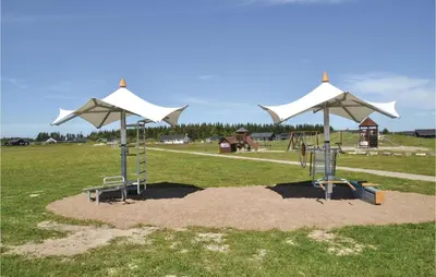 a playground with white umbrellas and a swing set at Holiday Home Kronvildtvej Brovst in Brovst