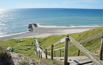 a wooden staircase leading to a beach with the ocean at Holiday Home Strandvejen Harboøre X in Harboør