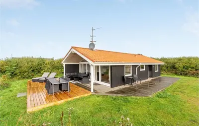 a small house with a deck in a field at Holiday Home Hermodsvej Harboøre Xi in Harboør