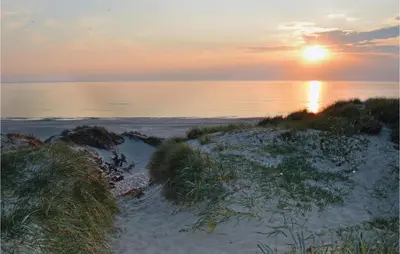 a sunset over a beach with the ocean and the sun at Holiday Home Viktoriavej Harboøre Ii in Harboør