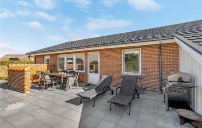 a patio with chairs and a grill and a house at Holiday Home Viktoriavej Harboøre Ii in Harboør
