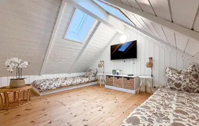 a attic room with a bed and a tv at Holiday Home Gloryvej Harboøre Iv in Harboør