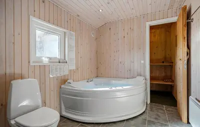 a bathroom with a white tub and a toilet at Holiday Home Vejlby Klit Harboøre V in Harboør