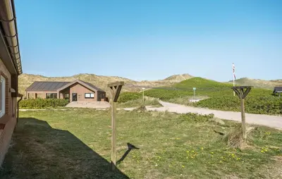 a house with two poles in the grass next to a road at Gorgeous Home In Harboøre With Sauna in Harboør