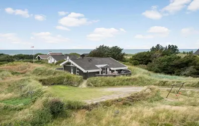 a house on a hill with the ocean in the background at Holiday Home Monasvej Løkken Iv in Løkken