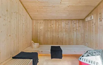 a wooden sauna with two black towels sitting in it at Holiday Home Monasvej Løkken Iv in Løkken