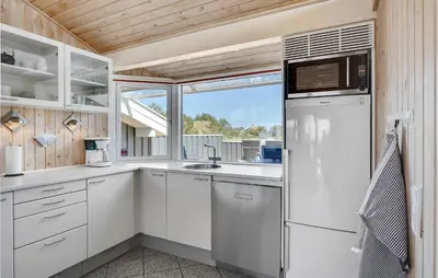 a kitchen with white cabinets and a large window at Holiday Home Monasvej Løkken Iv in Løkken