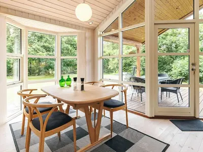 a dining room with a table and chairs and windows at 6 person holiday home in Løgstør in Løgsted