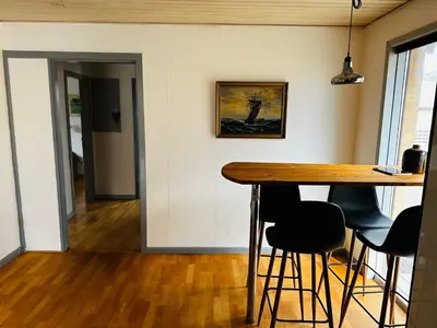 a dining room with a wooden table and bar stools at Beautiful villa close to beach and nature in Hanstholm