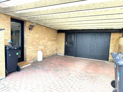a garage with two black doors and a brick wall at Beautiful villa close to beach and nature in Hanstholm