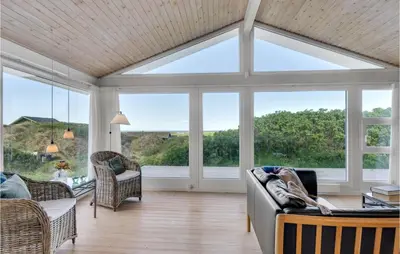 a living room with large windows and a couch at Holiday Home Monasvej Xii in Løkken