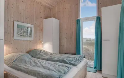 a bedroom with a bed and a large window at Holiday Home Monasvej Xii in Løkken