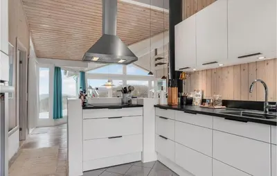 a kitchen with white cabinets and a silver ceiling at Holiday Home Monasvej Xii in Løkken
