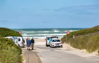a group of people walking down a road next to the beach at Pynten in Løkken