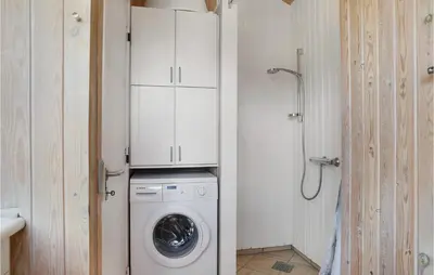 a washer and dryer in a bathroom with a shower at Pynten in Løkken