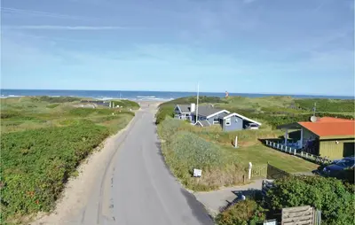 a dirt road next to houses on the beach at Pynten in Løkken