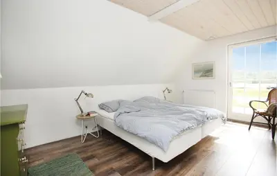 a white bedroom with a bed and a window at Holiday Home Rødhus Klitvej in Pandrup