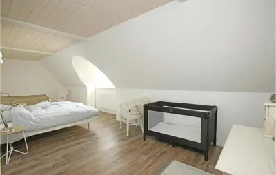 a bedroom with a bed and a table and chairs at Holiday Home Rødhus Klitvej in Pandrup