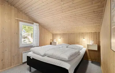 a bedroom with a large bed in a wooden room at 4 Bedroom Awesome Home In Saltum in Saltum