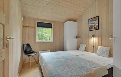 a small bedroom with a bed and a chair at Holiday Home Jægerens Vej in Blokhus