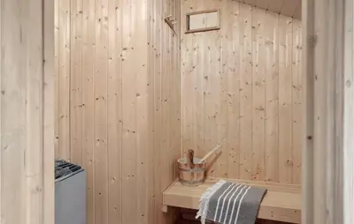 a bathroom with a wood paneled wall with a wooden tub at Holiday Home Kristavej Løkken Xii in Løkken