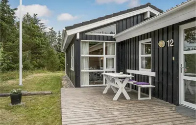 a black tiny house with a picnic table on a deck at Holiday Home Stellavej Løkken Denm in Løkken