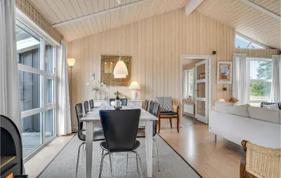 a dining room and living room with a table and chairs at Holiday Home Stellavej Løkken Denm in Løkken