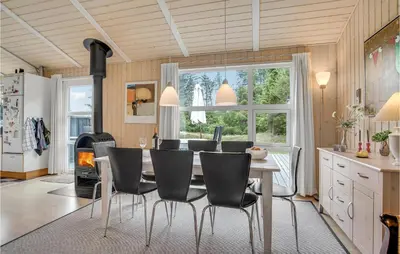 a kitchen with a table and chairs and a fireplace at Holiday Home Stellavej Løkken Denm in Løkken
