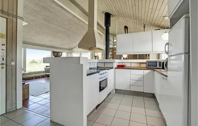 a kitchen with white cabinets and a large window at Awesome Home In Blokhus With Wifi in Blokhus